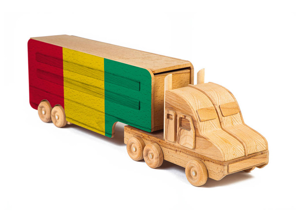 Close-up van een houten speelgoedauto met een geschilderde nationale vlag Guinee. Het concept van export-import, transport, nationale levering van goederen  - Foto, afbeelding