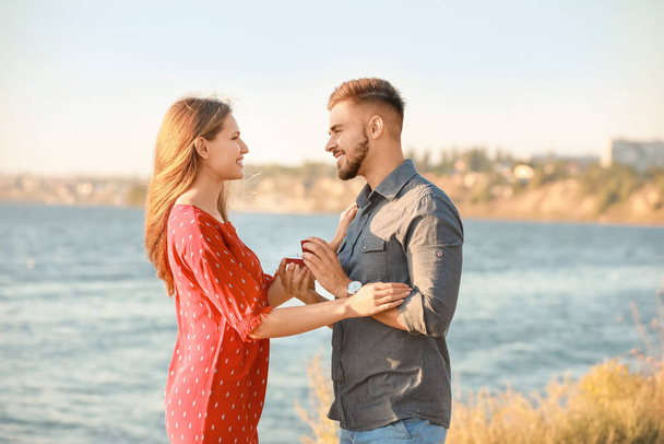 Young man proposing to his beloved near river - Foto, imagen