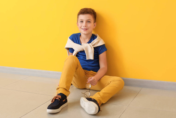 Roztomilý módní chlapec sedí v blízkosti barevné stěny - Fotografie, Obrázek