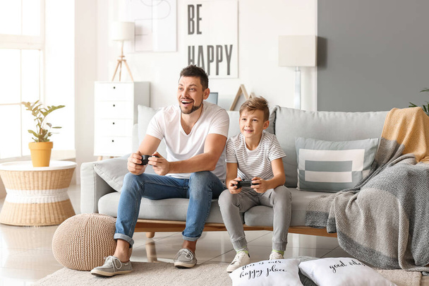 Vader en zijn zoontje spelen thuis videospelletjes - Foto, afbeelding