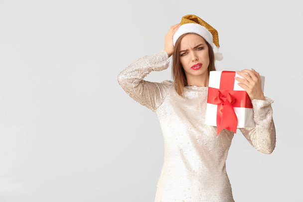 Drunk woman with Santa Claus hat and gift on light background - Fotoğraf, Görsel