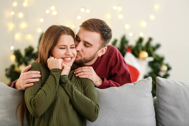 Ευτυχισμένο νεαρό ζευγάρι που αναπαύεται στο σπίτι παραμονή Χριστουγέννων - Φωτογραφία, εικόνα