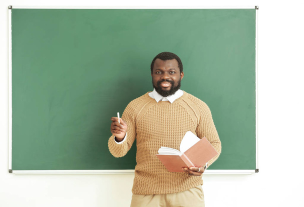 Afro-Amerikaanse leraar in de buurt van schoolbord in de klas - Foto, afbeelding