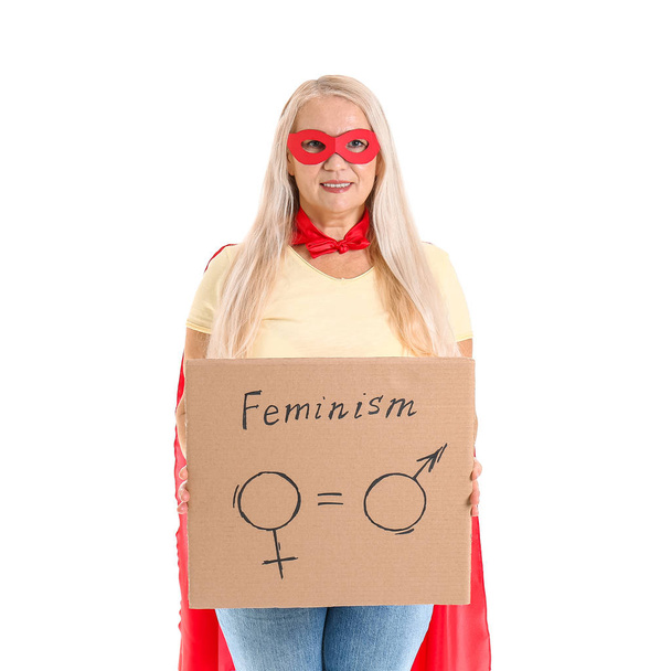 Dama en traje de superhéroe sosteniendo cartón con símbolos de hombre y mujer sobre fondo blanco. Concepto de feminismo
 - Foto, imagen