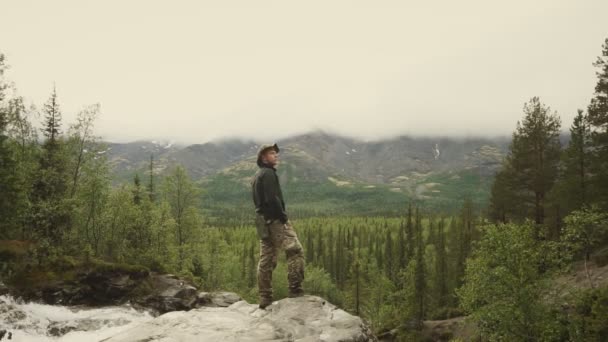 Ένας τουρίστας ή ένας ταξιδιώτης θαυμάζει μια όμορφη θέα του φυσικού τοπίου που στέκεται στην κορυφή ενός βουνού - Πλάνα, βίντεο