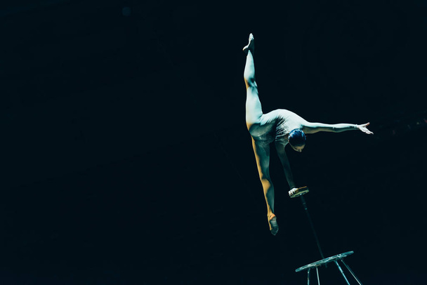 KYIV, UKRAINE - NOVEMBER 1, 2019: Gymnast doing split and handstand in circus isolated on black - Foto, Imagem