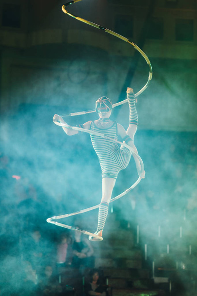 KYIV, UKRAINE - NOVEMBER 1, 2019: Back view of air gymnast performing in smoke in circus - Photo, Image