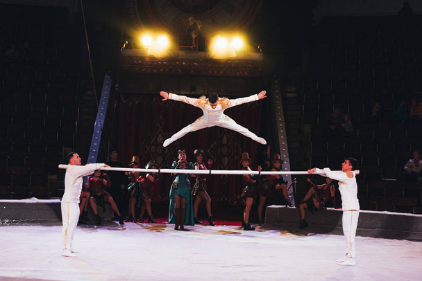 KYIV, UKRAINE - NOVEMBER 1, 2019: Air gymnast jumping above pole with artists at circus stage - Photo, Image