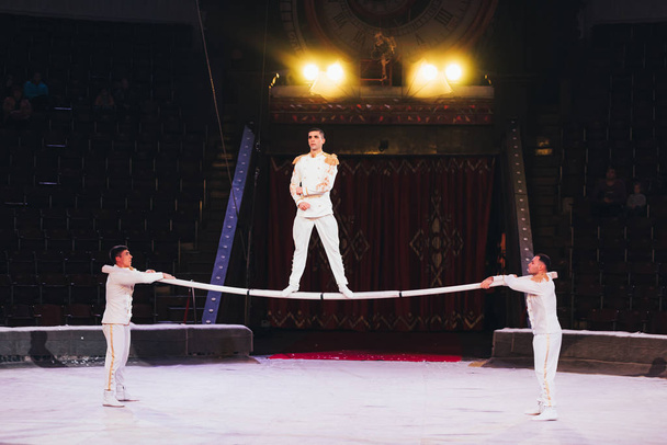 KYIV, UKRAINE - NOVEMBER 1, 2019: Three gymnasts performing with pole at circus arena - Photo, Image