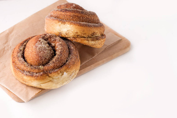two cinnamon rolls on a wooden board on a white background. copy space - Foto, immagini