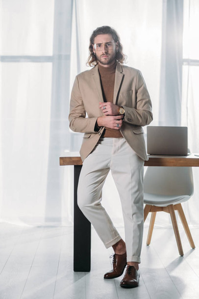 elegant fashionable businessman standing near desk in office - Photo, Image