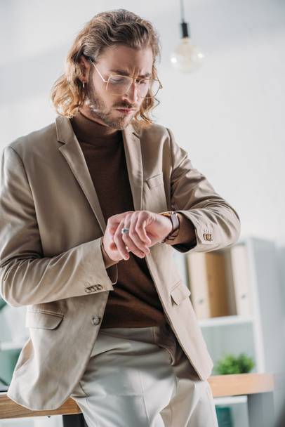elegant fashionable businessman looking at wristwatch - Zdjęcie, obraz