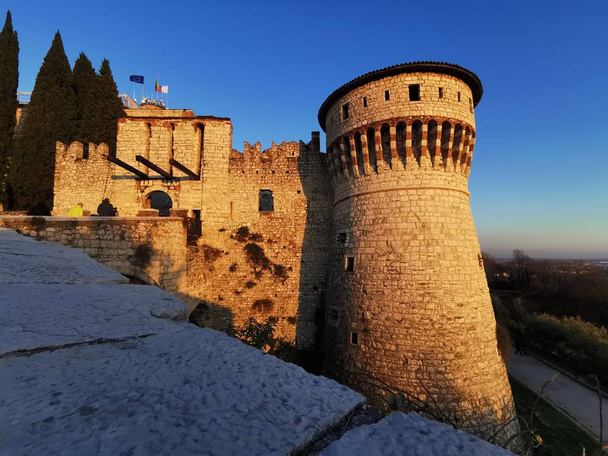 Muralhas do castelo de Brescia e torre fortificada ao pôr-do-sol
 - Foto, Imagem