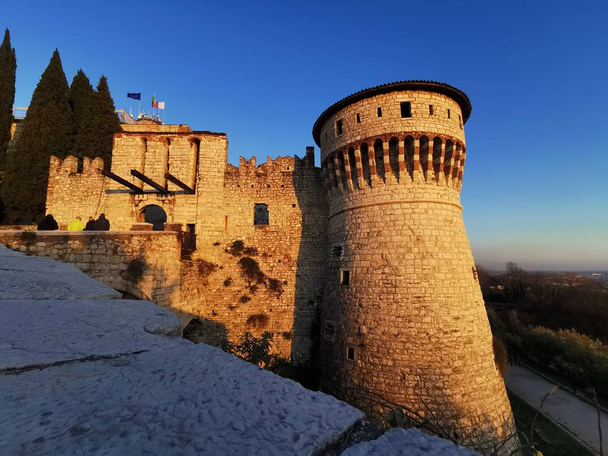 Brescian linnan muurit ja linnoitettu torni auringonlaskun aikaan
 - Valokuva, kuva