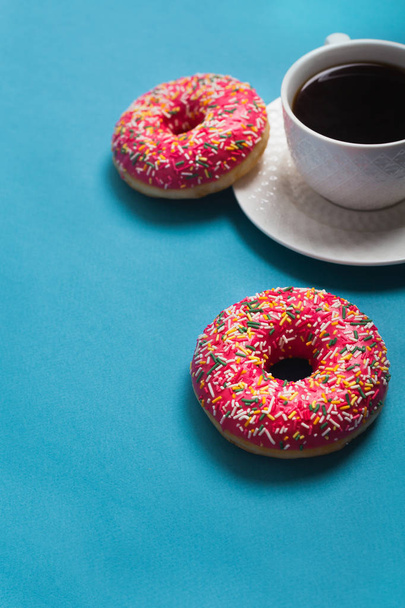 A cup of americano with two pink donuts on a blue background - Foto, Bild