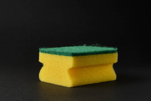 single new yellow sponge against black background - Foto, afbeelding