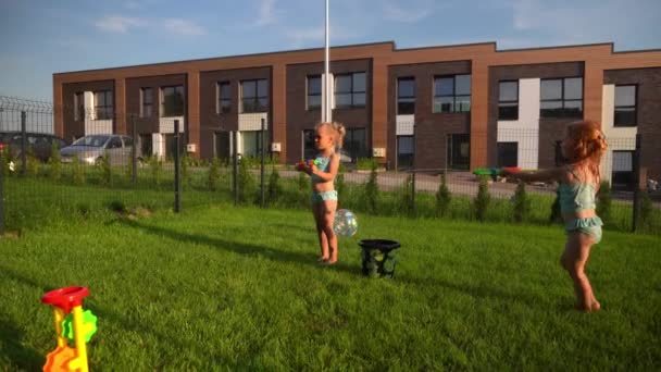 Die besten Freundinnen der verspielten Mädchen planschen mit Wasserpistolen im Hof des Hauses. Aktive Kinder - Filmmaterial, Video