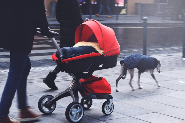 Apa piros baba babakocsi sétál az utcán a feleségével egy - Fotó, kép