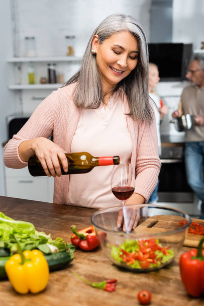 selective focus of smiling asian woman pouring wine to glass  - Photo, Image