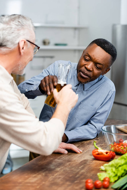 messa a fuoco selettiva di afro-americano uomo clinking con il suo amico in cucina
  - Foto, immagini