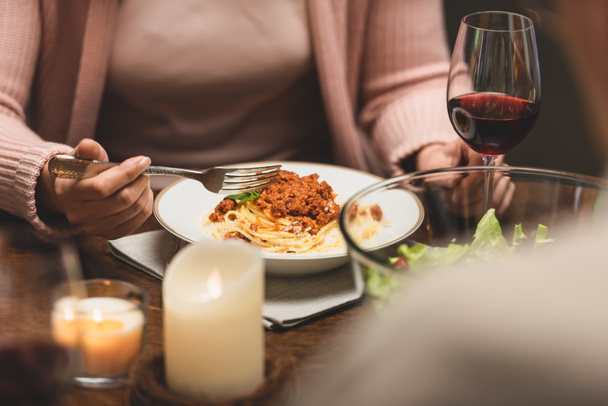 cropped view of woman sitting at table and eating pasta during dinner  - Photo, Image
