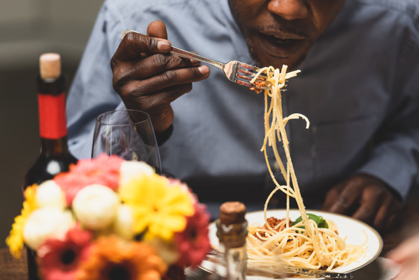 καλλιεργημένη άποψη της Αφρικής Αμερικανός άνθρωπος τρώει ζυμαρικά κατά τη διάρκεια του δείπνου  - Φωτογραφία, εικόνα