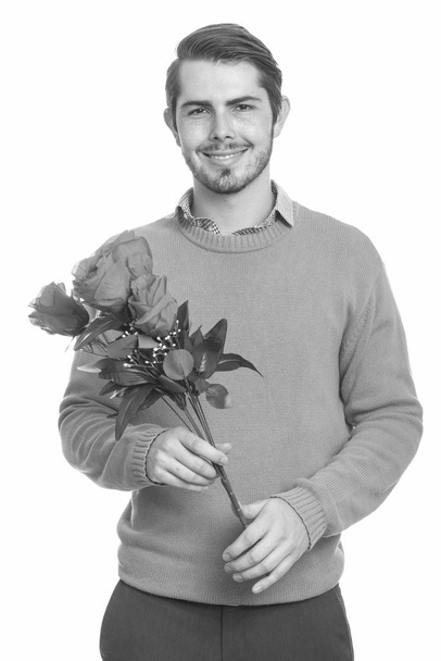 Young happy Caucasian man holding red roses ready for Valentines day - Photo, image