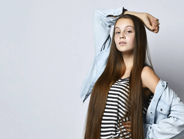 Teenage girl in striped t-shirt, denim jacket and pants. She looking at you, posing isolated on white studio background. Close up - Fotografie, Obrázek