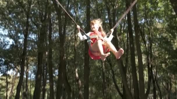 Gyermek lány ugrás rögzítve egy trambulinon a nyári parkban. - Felvétel, videó