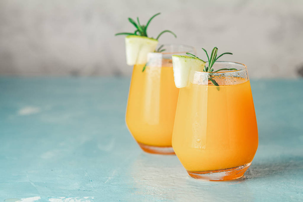 Žlutý oranžový koktejl s melounem a mátou ve skle na modrém betonovém pozadí, zblízka. Letní nápoje a alkoholické koktejly. Alkoholický nebo detoxikační koktejl. - Fotografie, Obrázek