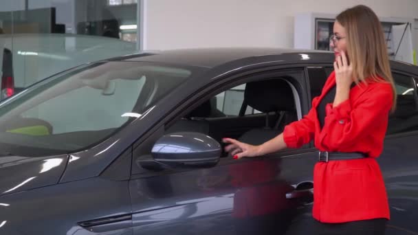 Beautiful woman with glasses talking on the phone at a car dealership - Materiaali, video