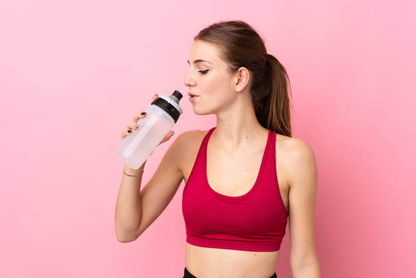 Young sport woman over isolated pink background with sports water bottle - 写真・画像