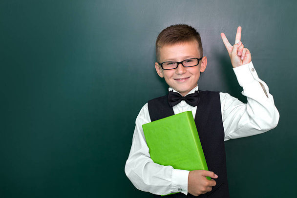 弓タイと彼の手の本とメガネで幸せなかわいい賢い男の子。学校には初めてだ学校に戻る. - 写真・画像