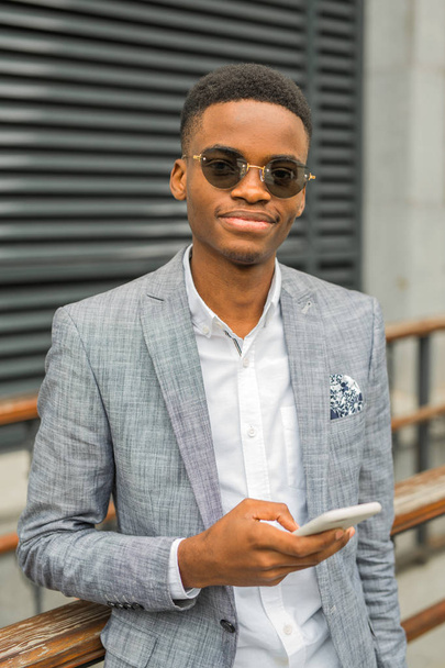 handsome young african man in a suit with a phone in his hand - Фото, зображення