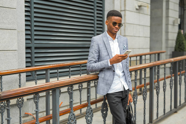 handsome young african man in a suit with a phone in his hand - Zdjęcie, obraz
