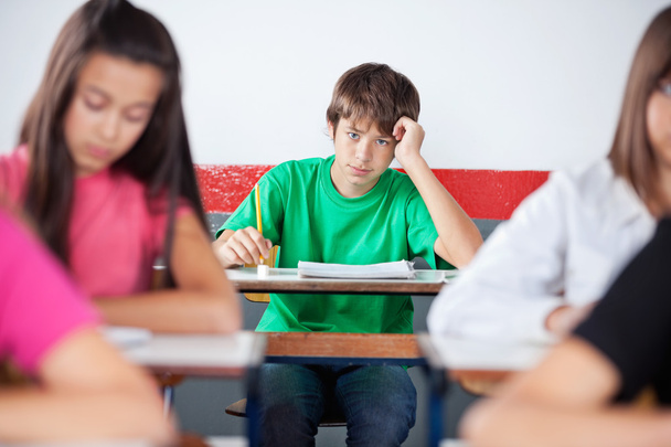 Teenage Male Student Leaning On Desk At Classroom - Foto, Imagem