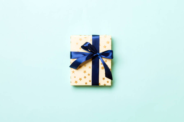 Top view woman hands holding Christmas present box with blue bow on blue background with copy space - Фото, зображення