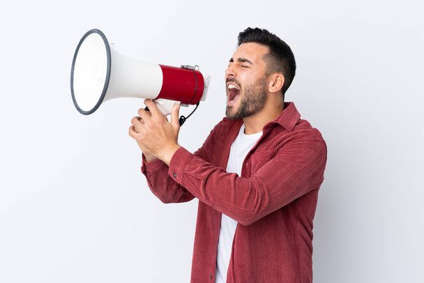 Young handsome man with beard wearing a corduroy jacket over isolated white background shouting through a megaphone - Foto, Imagem