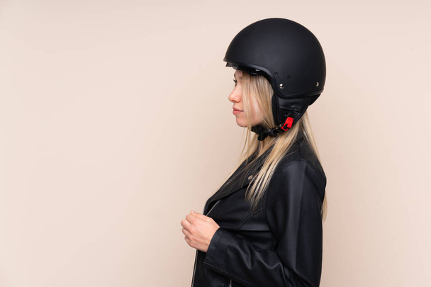 Young blonde woman with a motorcycle helmet over isolated backgr - Photo, image