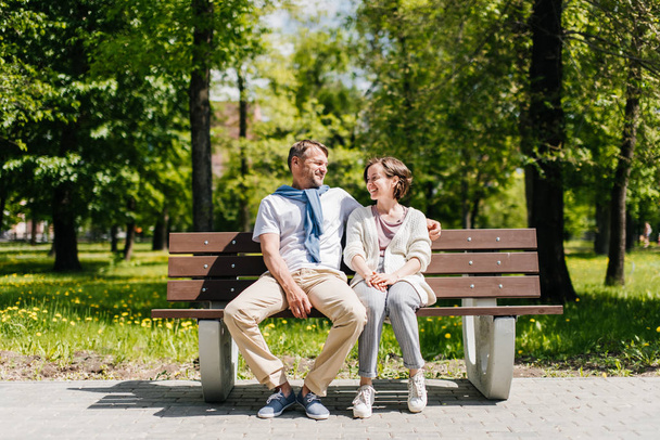 Couple marié d'âge moyen se reposant dans le parc tourné de loin
. - Photo, image