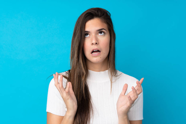 Teenager girl over isolated blue background frustrated by a bad situation - Foto, afbeelding