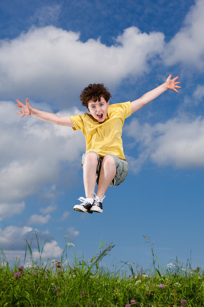Boy jumping, running against blue sky - Фото, изображение
