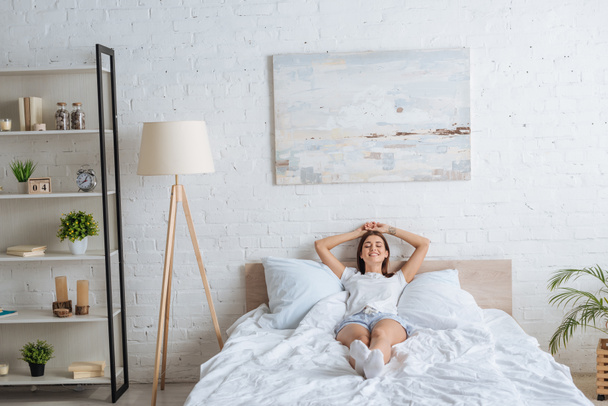 happy woman with tattoo lying while resting in bedroom  - Photo, Image