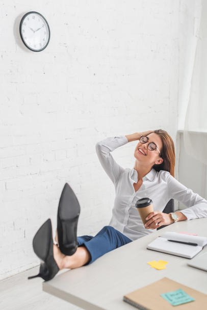 enfoque selectivo de la mujer de negocios feliz sosteniendo taza de papel mientras se enfría en la oficina
  - Foto, imagen