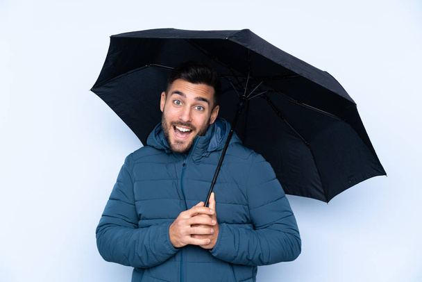 Чоловік тримає парасольку над ізольованим тлом з щасливим виразом
 - Фото, зображення