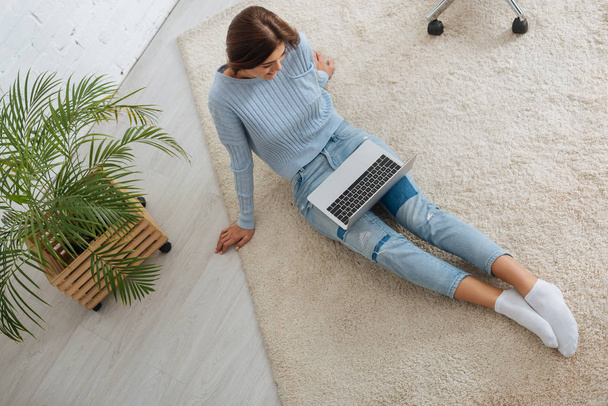 widok z góry blogger patrząc na laptopa podczas siedzenia na dywanie  - Zdjęcie, obraz