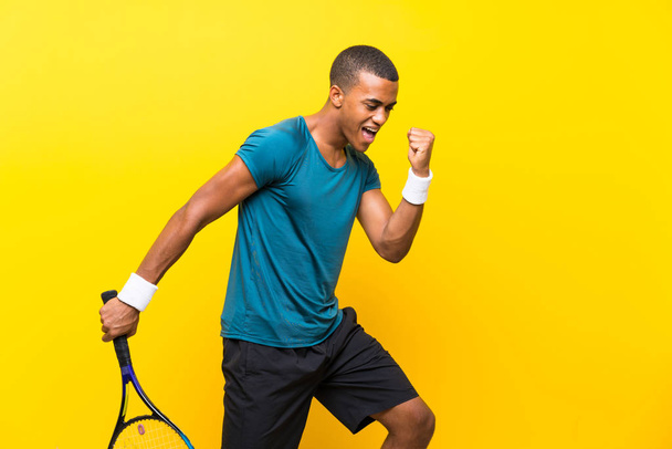 Afro American tennis player man over isolated yellow background - 写真・画像