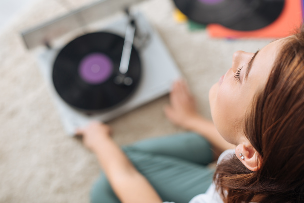 selective focus of dreamy girl listening music near vintage record player  - 写真・画像