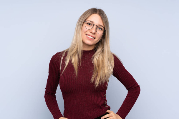 Young blonde woman over isolated blue background with glasses and happy - Foto, imagen