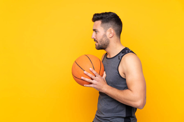 Άνθρωπος πάνω από απομονωμένο κίτρινο φόντο παίζει μπάσκετ - Φωτογραφία, εικόνα